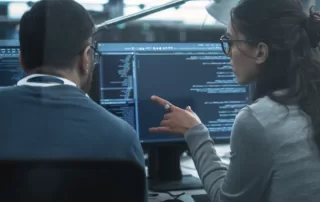 Two co-workers looking at data on a computer screen.